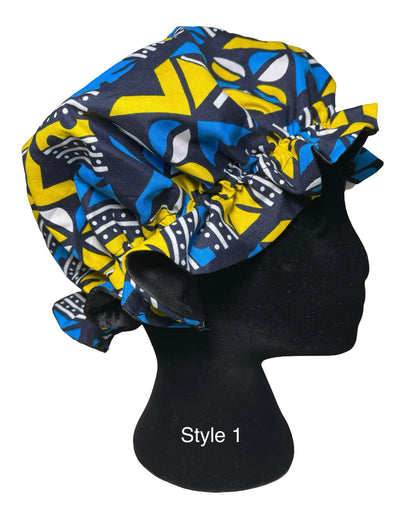 A bonnet with a bold geometric pattern in blue, yellow, and black, displayed on a black mannequin head against a white background.