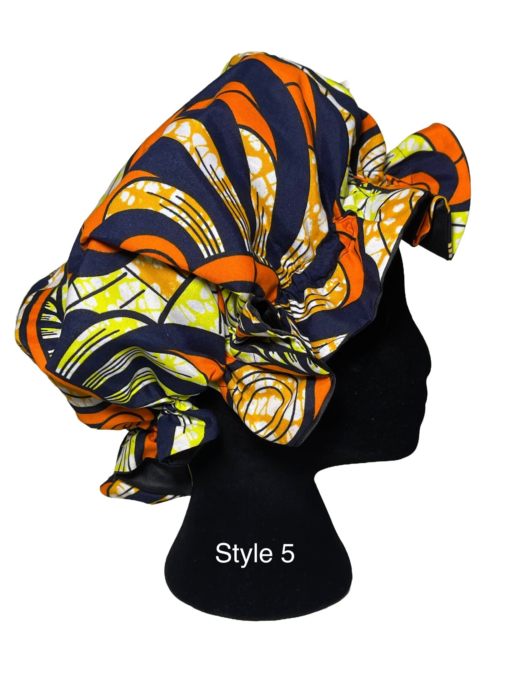 A multicolor African print bonnet hat styled on a black mannequin head, featuring a bold pattern of orange, navy blue, yellow, and white. The text 'Style 5' is printed on the black mannequin stand.
