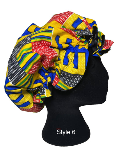 A multicolor African wax print bonnet styled on a black mannequin head, featuring yellow, blue, red, green, and black patterns. The text 'Style 6' is printed on the black mannequin stand.