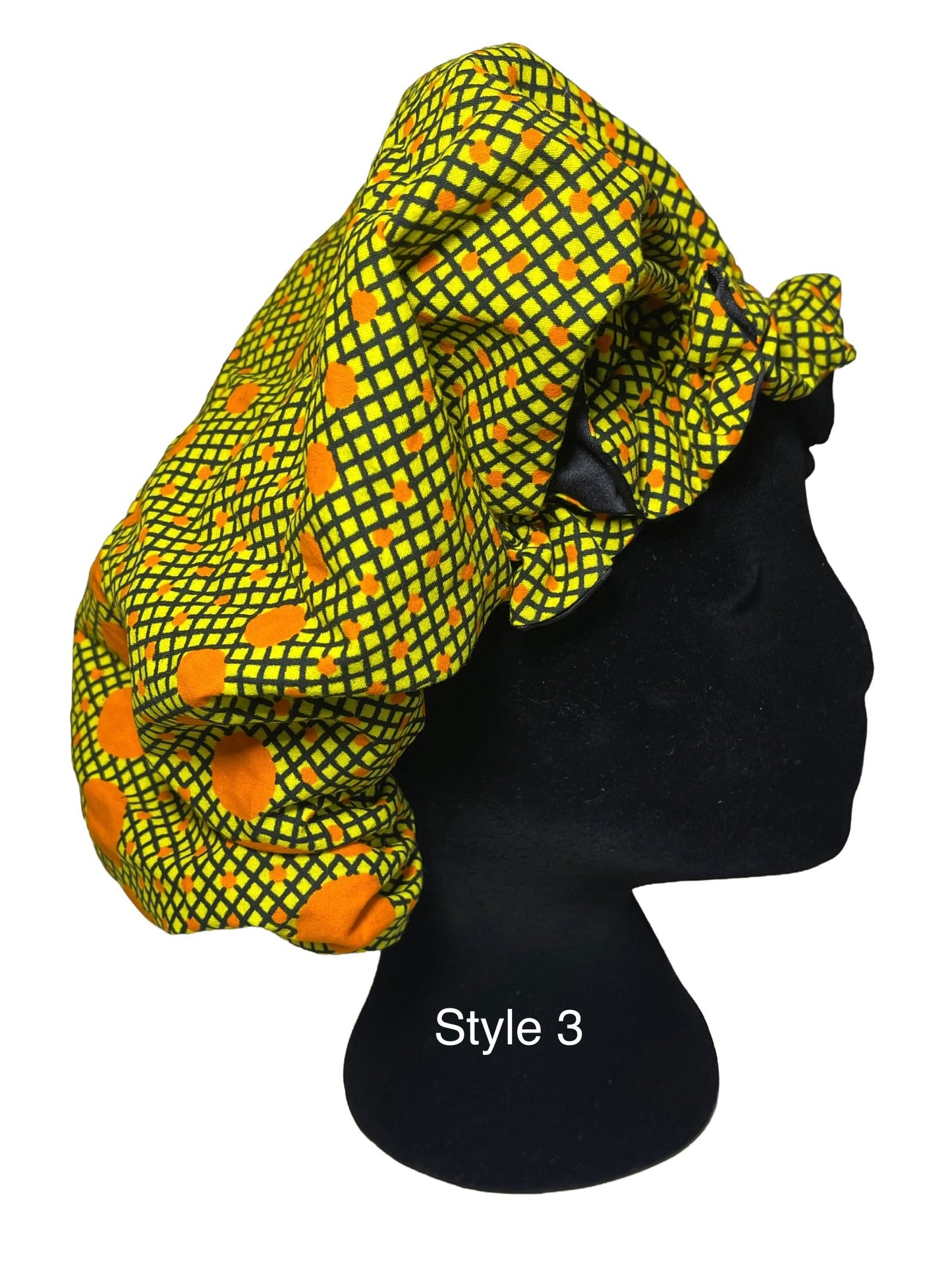 A black mannequin head wearing a bright yellow and green patterned fabric bonnet with orange circular motifs, shown against a plain white background with the text 'Style 3' on the mannequin.