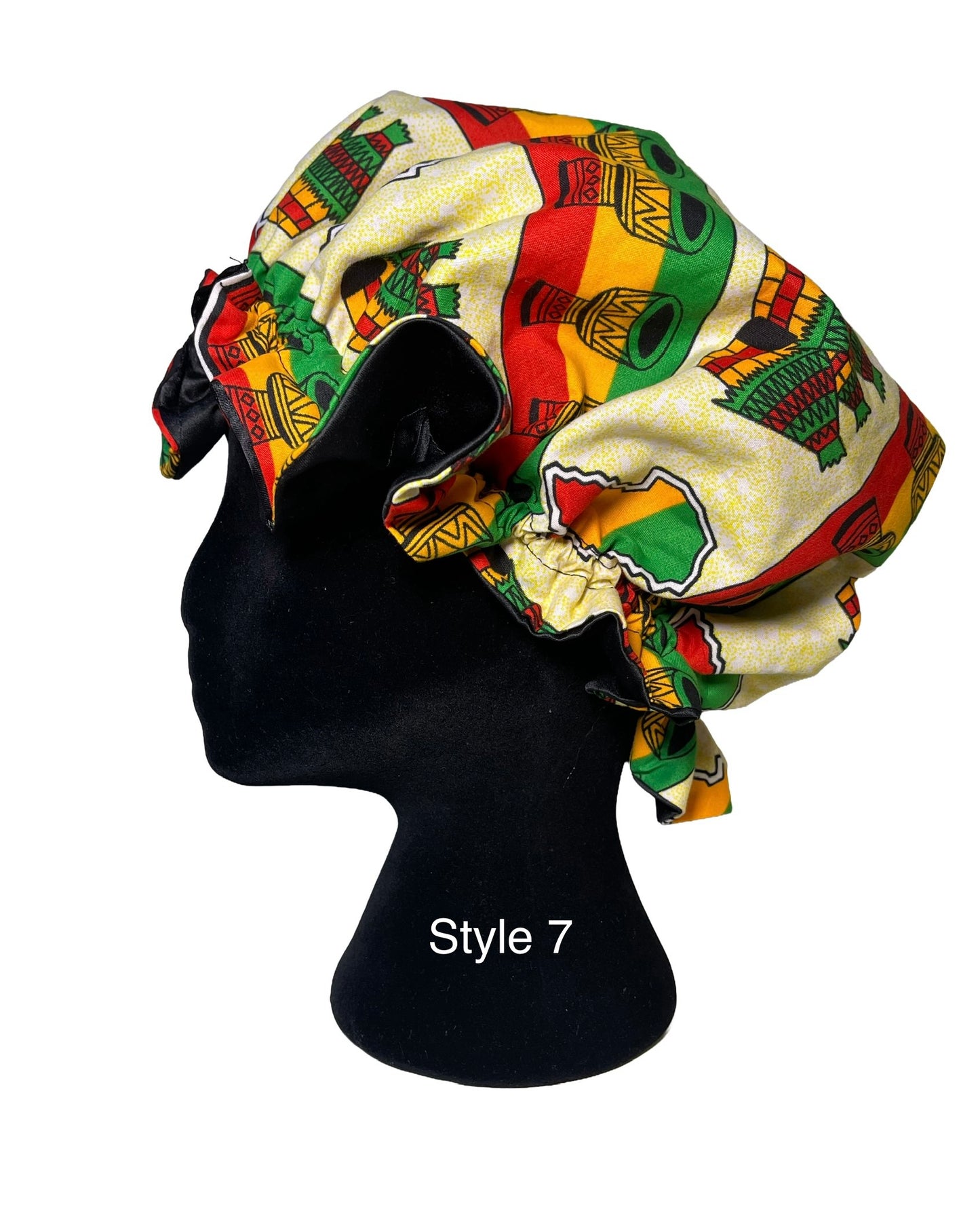 A fabric bonnet with a vibrant African-inspired pattern in red, yellow, green, and cream, displayed on a black mannequin head. The text 'Style 7' is printed on the mannequin neck.