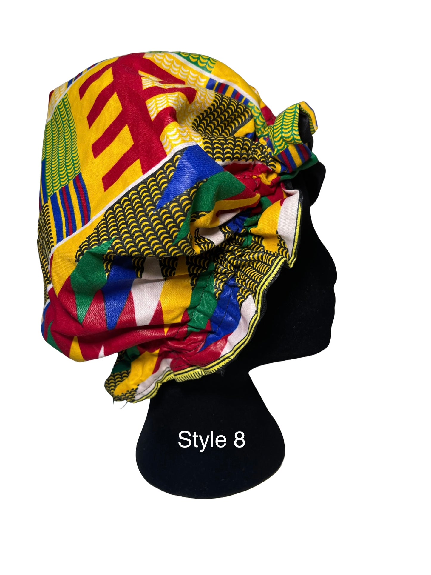 A multicolor African wax print bonnet styled on a black mannequin head, featuring geometric patterns in yellow, red, green, blue, and white. The text 'Style 8' is printed on the black mannequin stand.