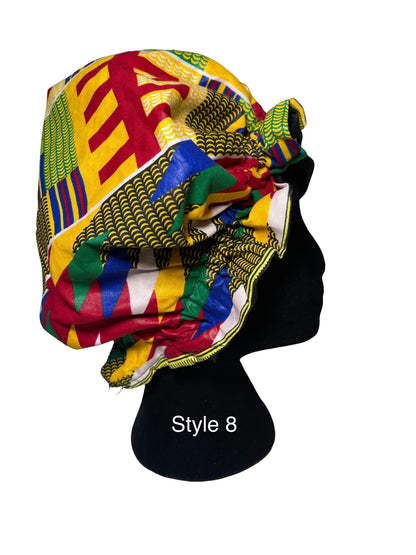 A multicolor African wax print bonnet styled on a black mannequin head, featuring geometric patterns in yellow, red, green, blue, and white. The text 'Style 8' is printed on the black mannequin stand.
