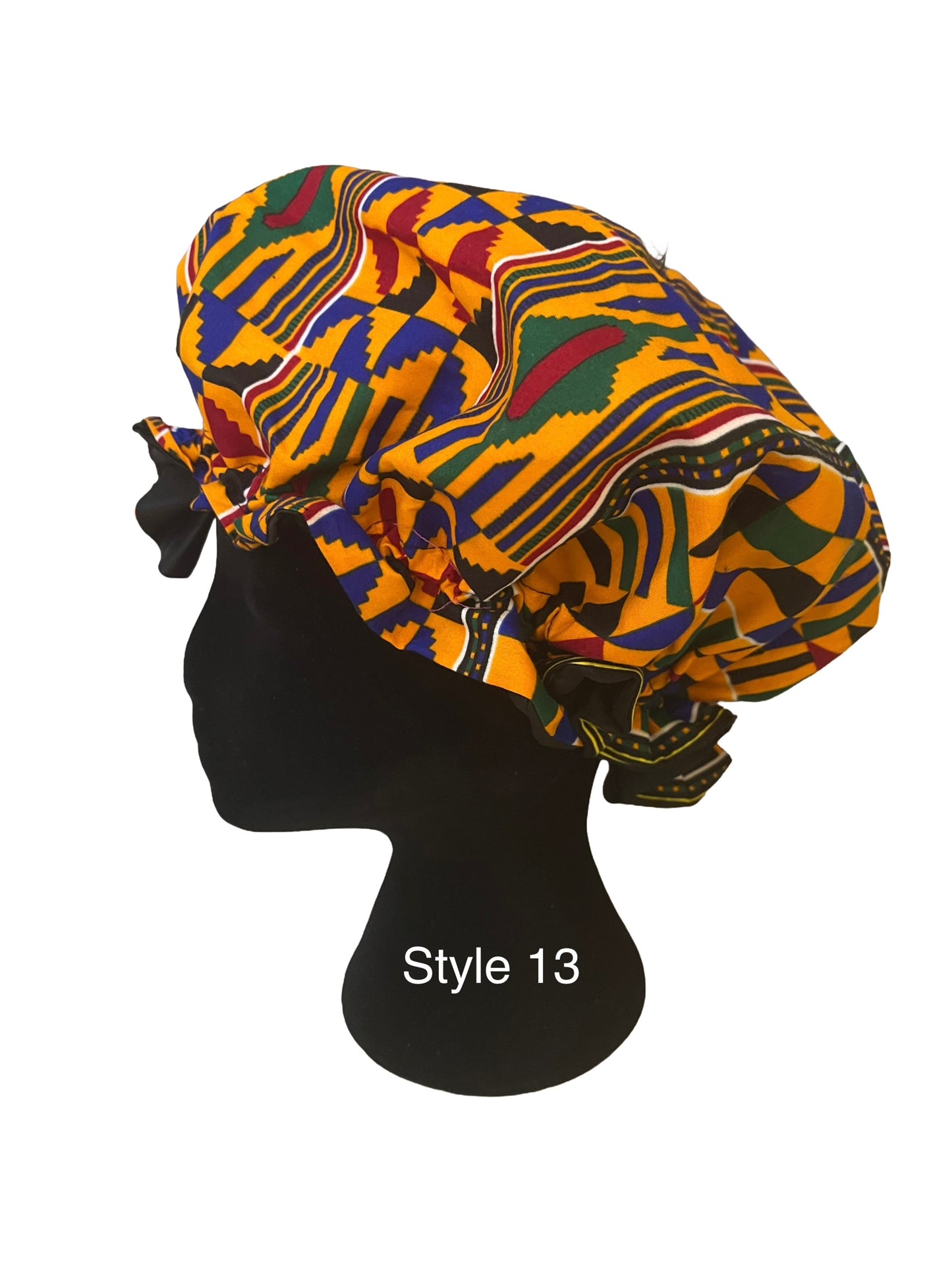 A multicolor African wax print bonnet displayed on a black mannequin head. The pattern features yellow, green, blue, red, and black geometric designs.