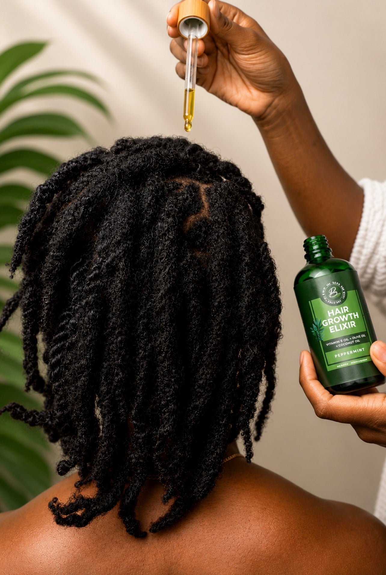 A person shown from the back with long black dreadlocks, while another hand holds a dropper above the hair and a green bottle labeled Hair Growth Serum is visible in the other hand. A soft beige wall and green plant leaves appear in the background.